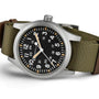 The Hamilton Khaki Field Mechanical 42mm is a soldier’s watch with a black dial, white numerals, green fabric strap, and both 12- and 24-hour markers for versatile timekeeping.