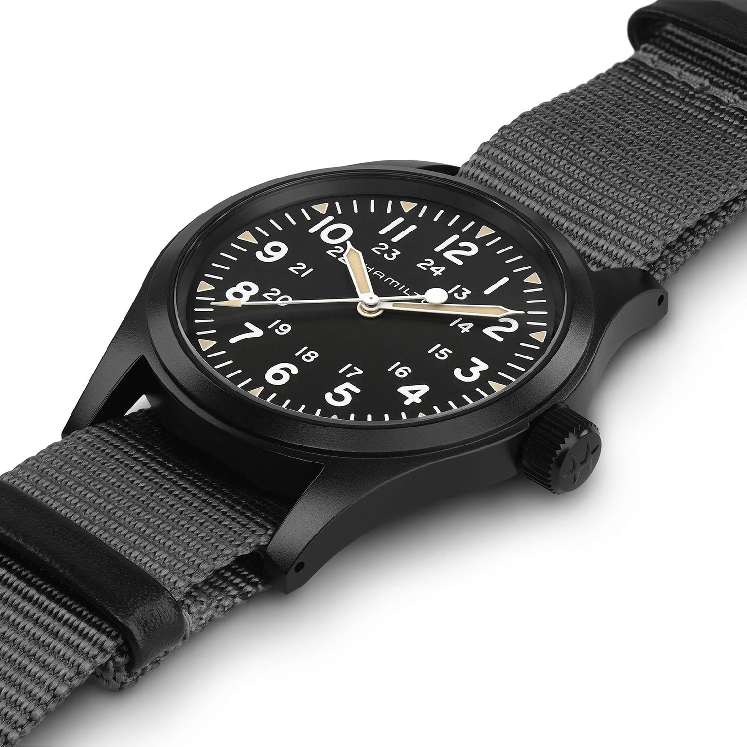 A Hamilton Khaki Field Mechanical wristwatch with white Arabic numerals, a black NATO strap, and a matte black case is displayed at an angle on a white background.