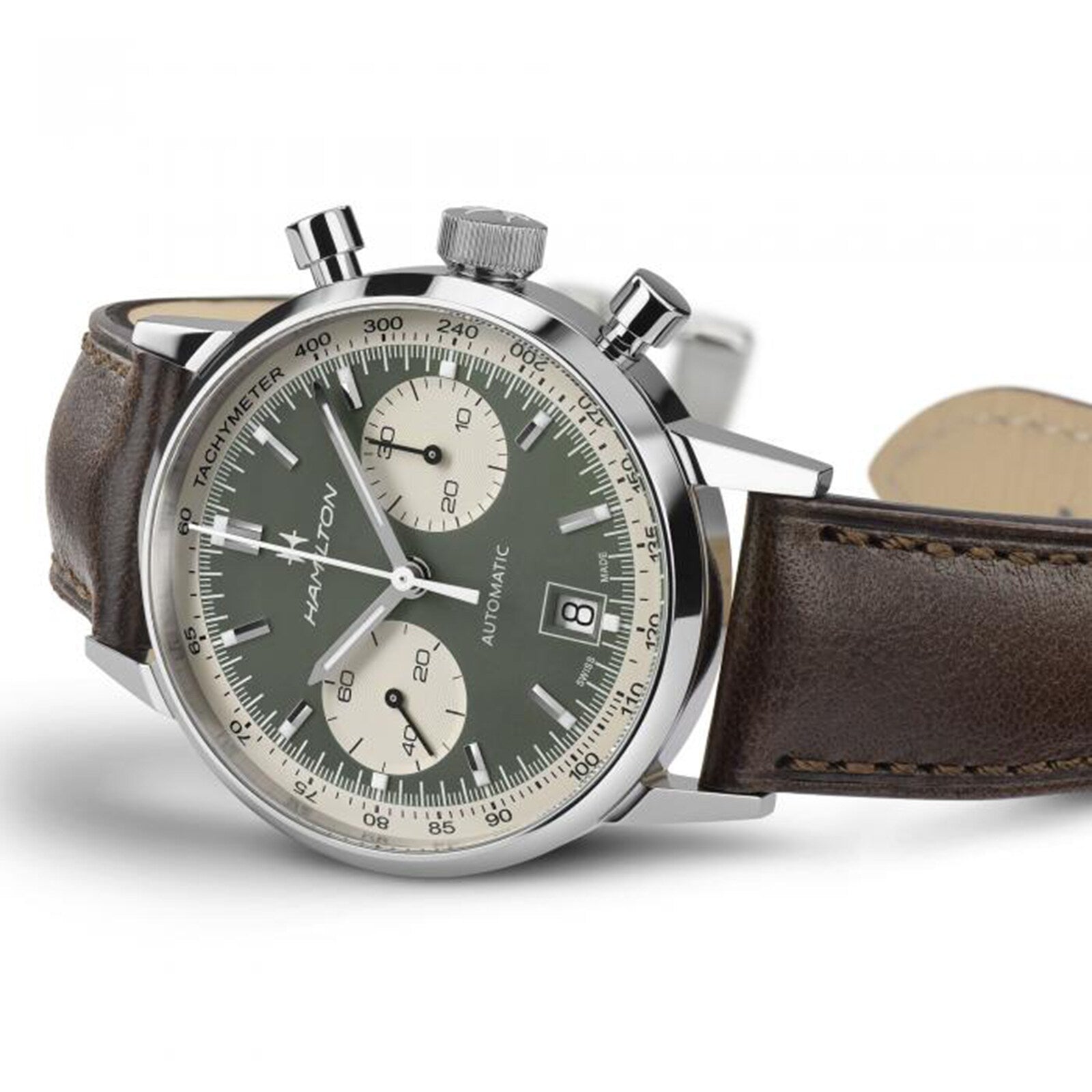 The Hamilton American Classic Intra-Matic Auto Chrono 40mm showcases vintage style with a green panda dial, two white subdials, date window, silver case, and brown leather strap, displayed at an angle.