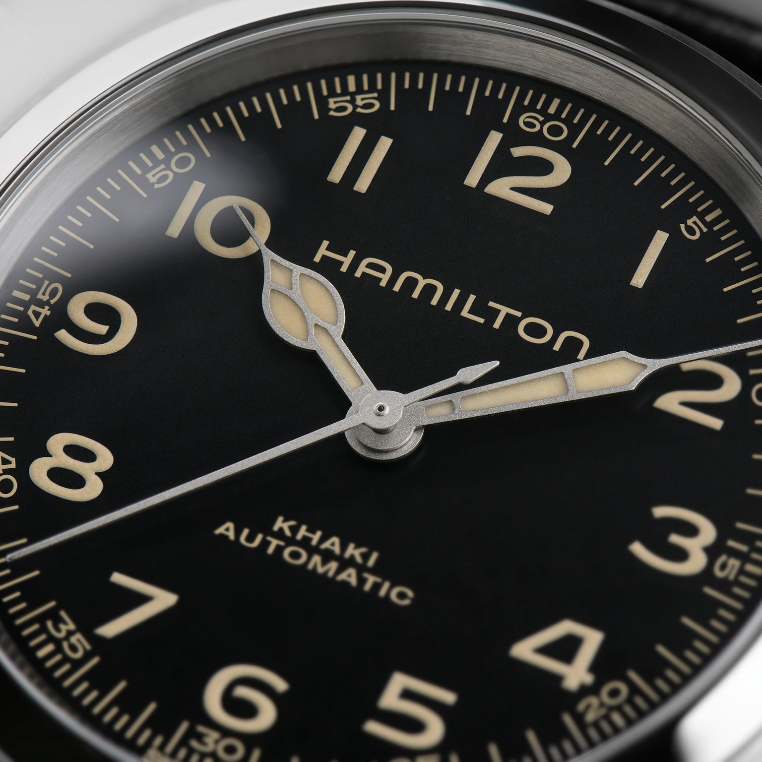Close-up of the Hamilton Khaki Field Murph 38mm watch face with beige numerals, sword-shaped hands, and minute markers on black, powered by an automatic movement offering an 80-hour power reserve.