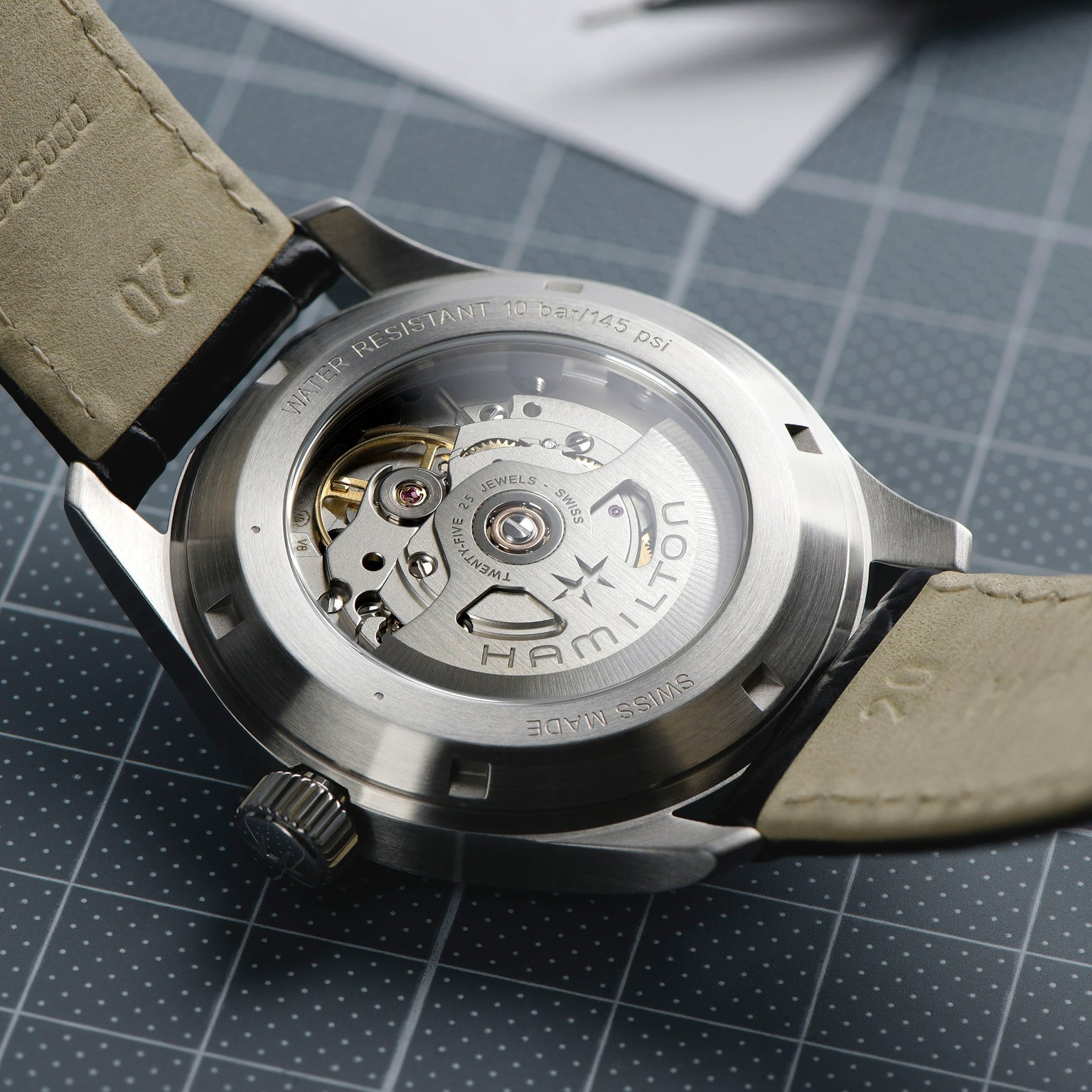 Close-up of the Hamilton Khaki Field Murph 38mms transparent case back reveals its automatic movement, visible gears, engraved details, and notable 80-hour power reserve.