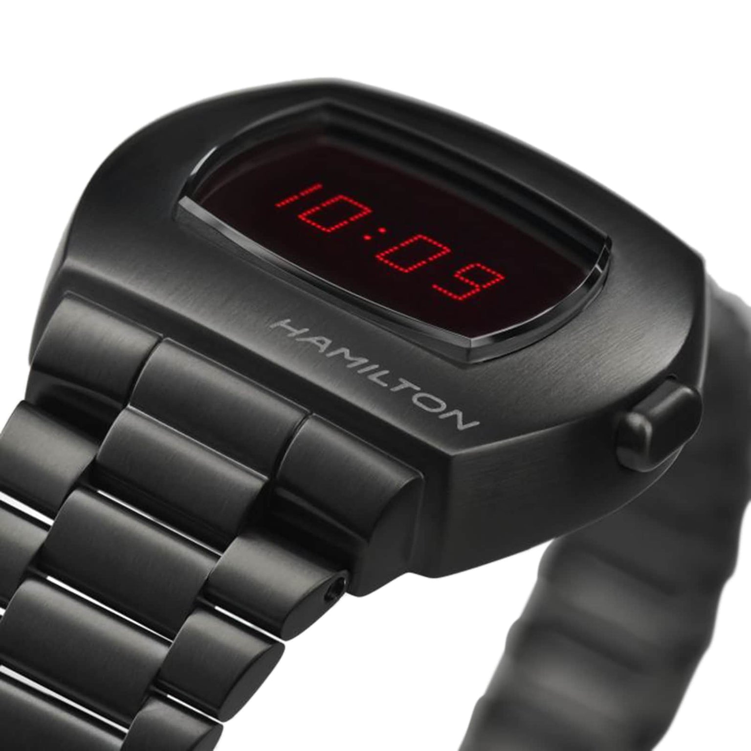A close-up of the Hamilton American Classic PSR Digital Quartz watch shows the time 10:09 in red digits on its hybrid LCD and OLED display.