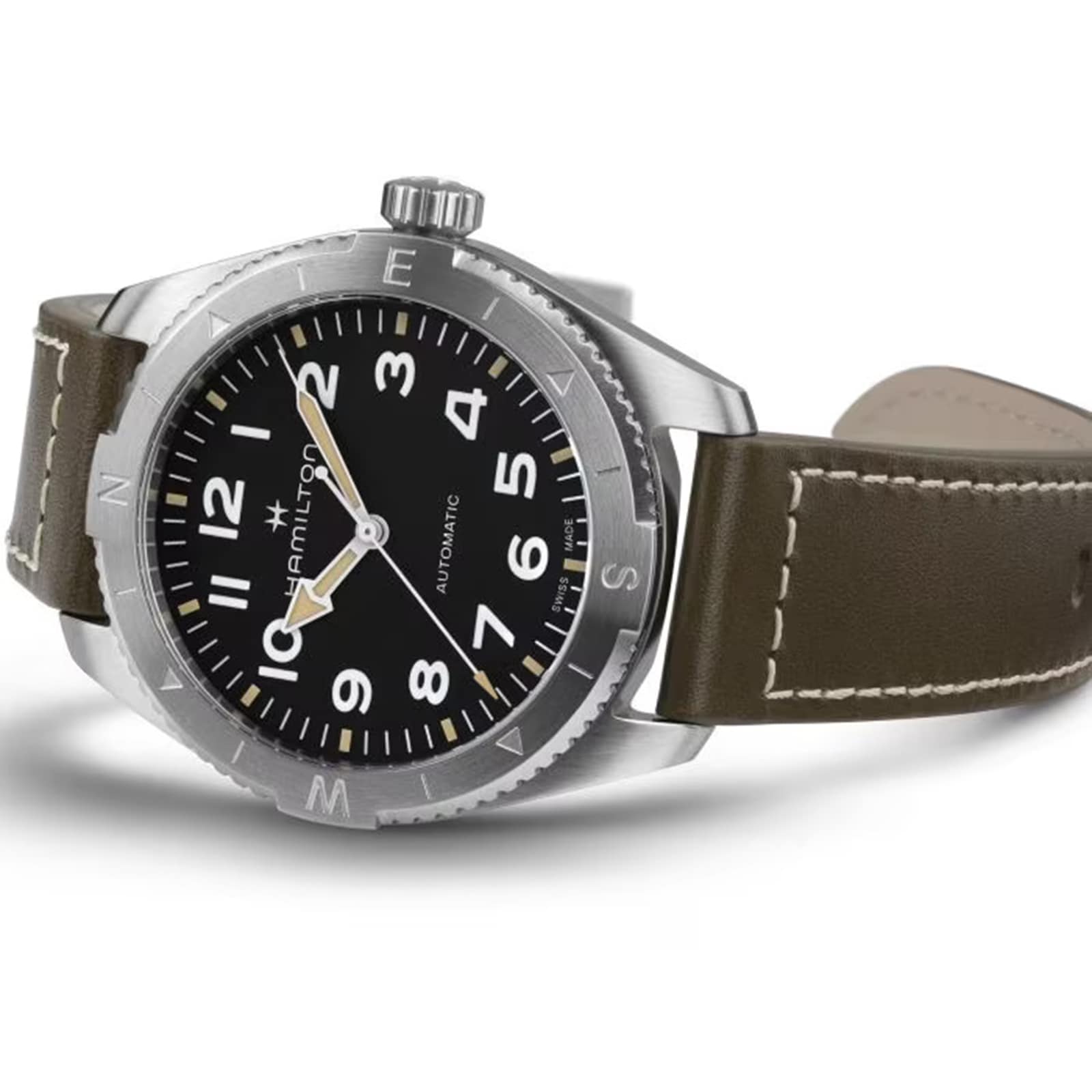 The Hamilton Khaki Field Expedition Auto is displayed on a white background, featuring a stainless steel case, Super-LumiNova® black dial with white numerals, and a brown leather strap.