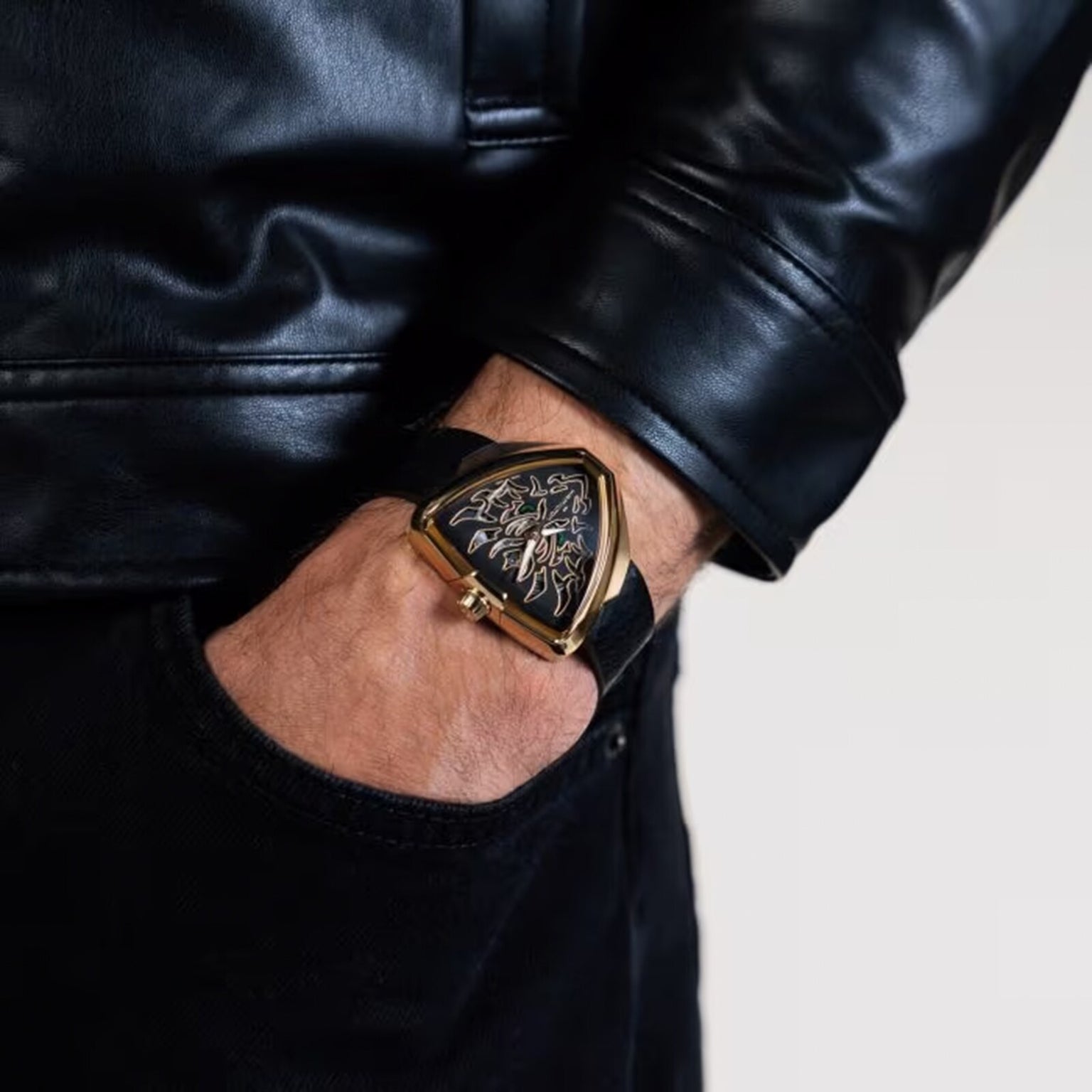 A person wearing a black leather jacket and a distinctive Hamilton Khaki Field King Auto watch, their hand in a pocket.
