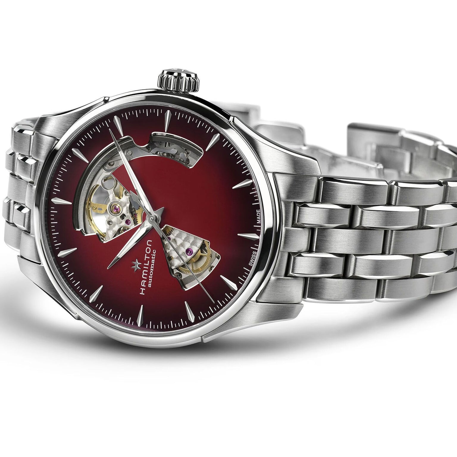 The Hamilton Jazzmaster Open Heart Auto is a stainless steel wristwatch with a red dial, exposed mechanical movement sections, and silver hour markers and hands. The Hamilton brand name is displayed on the face.