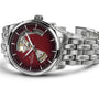 The Hamilton Jazzmaster Open Heart Auto is a stainless steel wristwatch with a red dial, exposed mechanical movement sections, and silver hour markers and hands. The Hamilton brand name is displayed on the face.