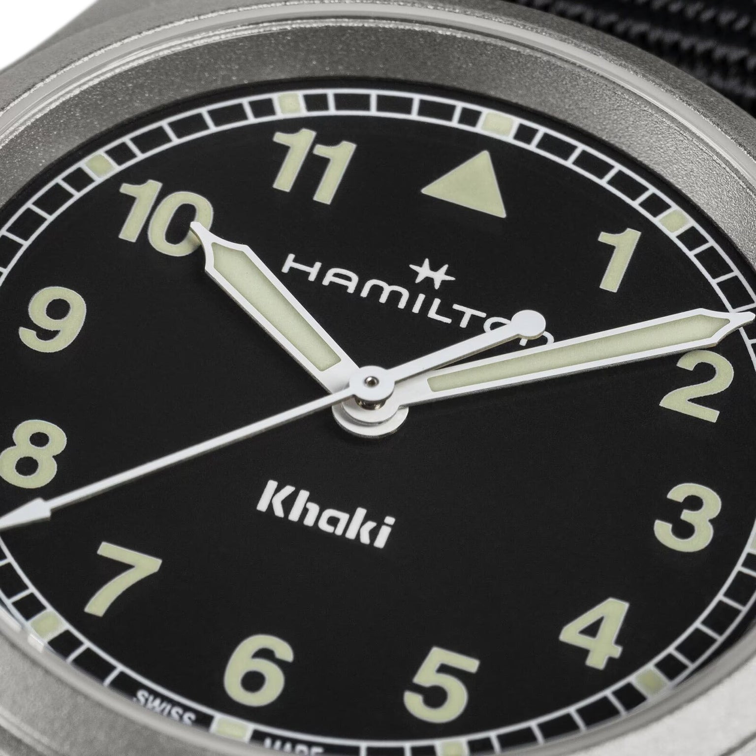 Close-up of the Hamilton Khaki Field Quartz 33mm watch face featuring luminous hands, Arabic numerals, and the brand’s logo on a black dial, showcasing its military heritage.