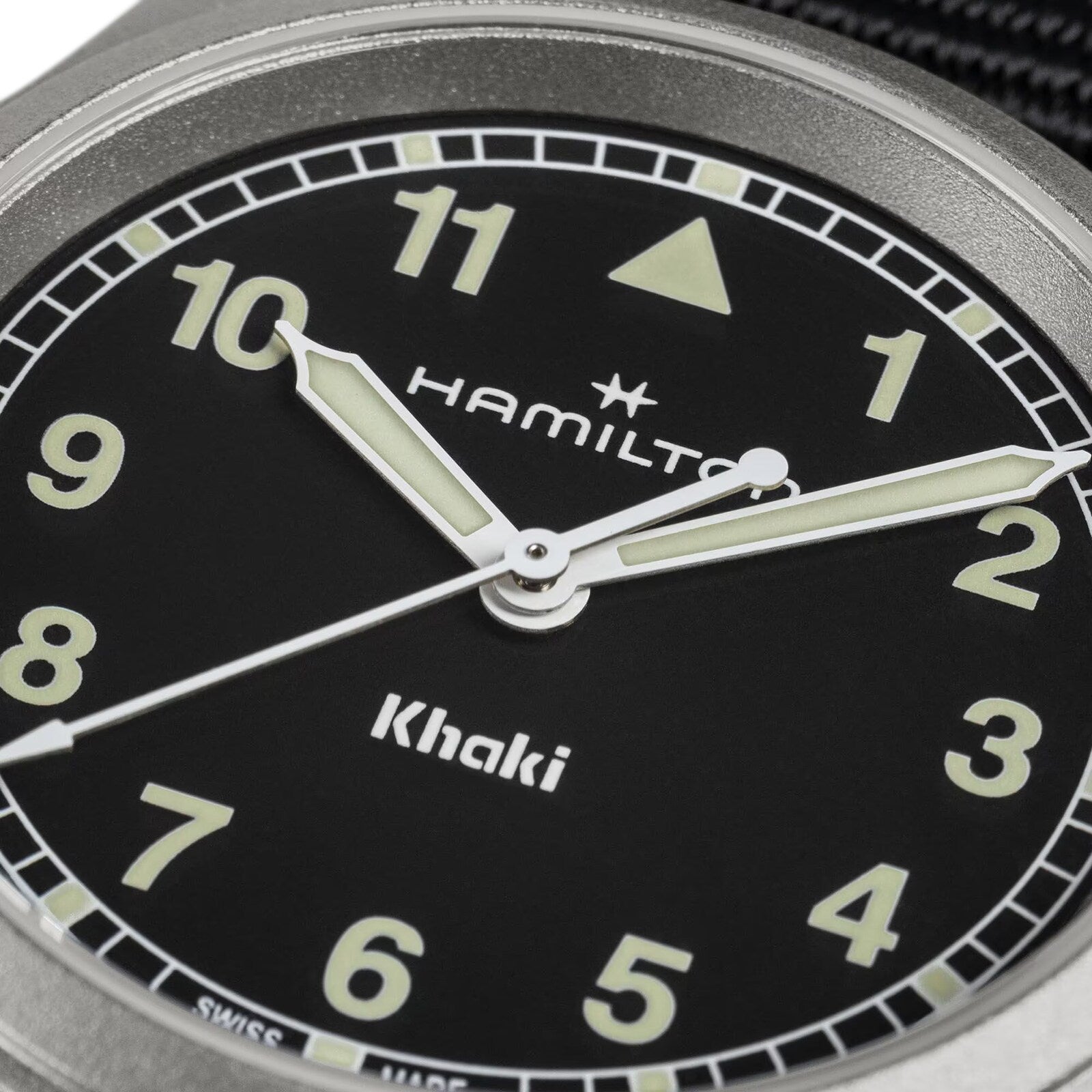 Close-up of the Hamilton Khaki Field Quartz 33mm watch face featuring luminous hands, Arabic numerals, and the brand’s logo on a black dial, showcasing its military heritage.