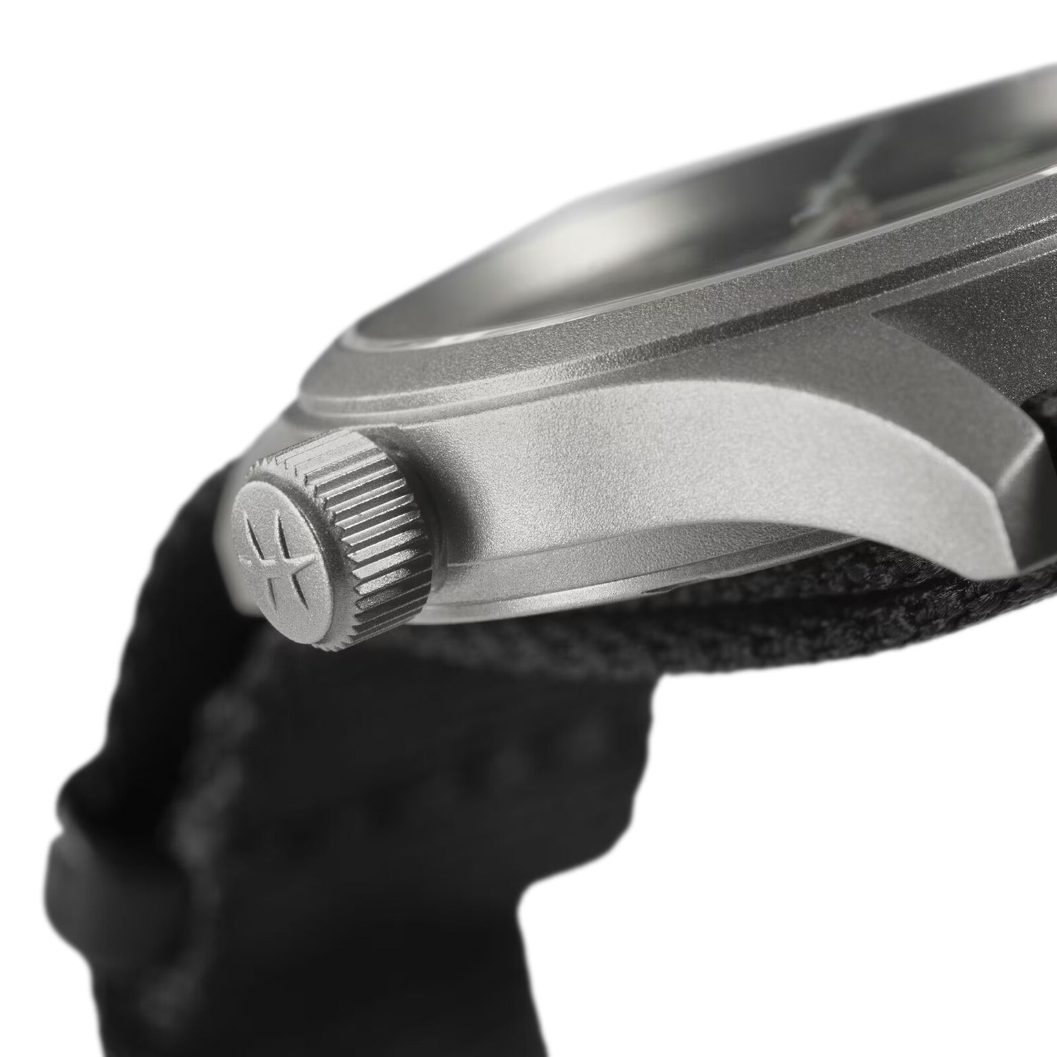 Close-up side view of the Hamilton Khaki Field Quartz 33mm, featuring a textured crown with logo, paired with a black NATO strap that underscores its military-inspired design.