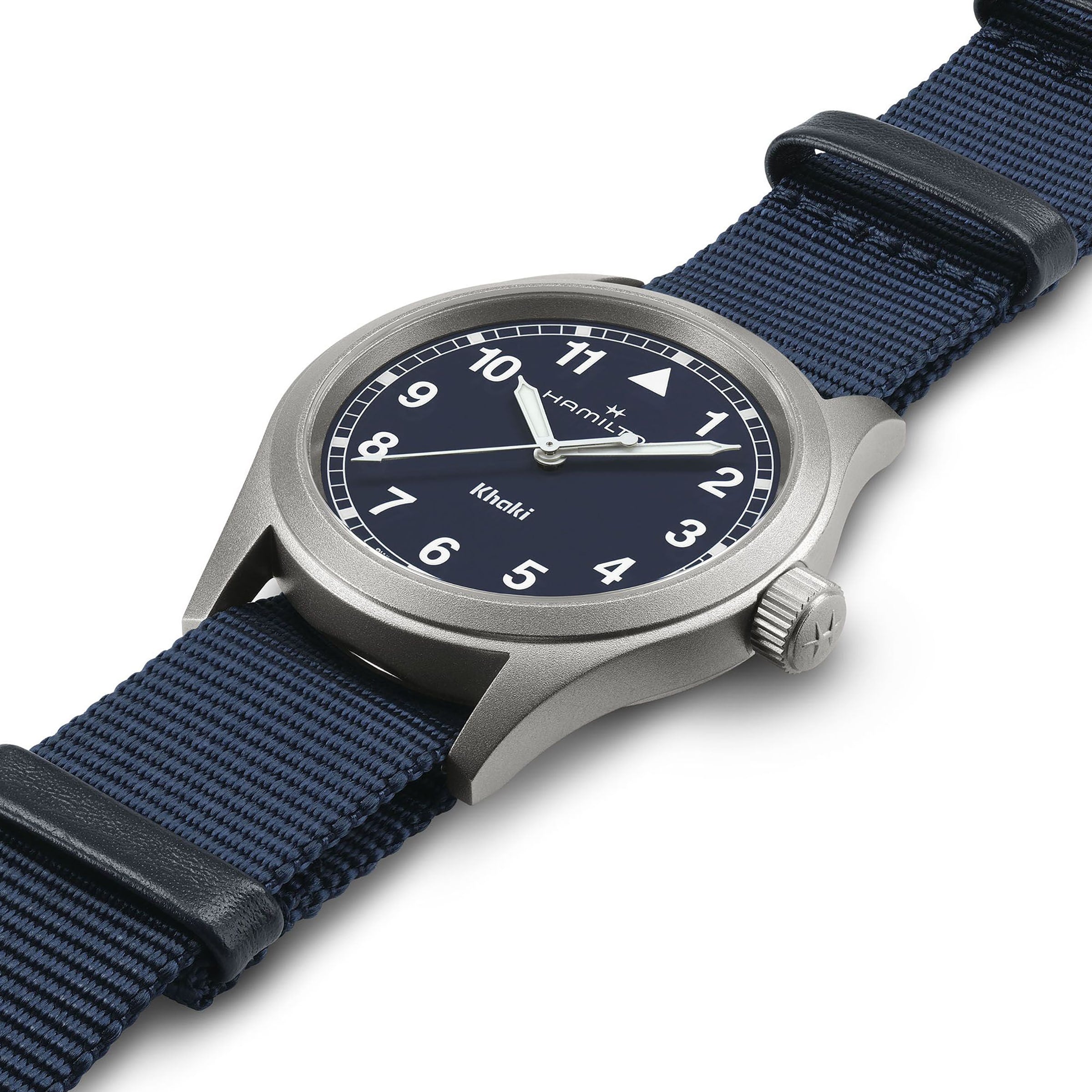 A Hamilton Khaki Field Quartz 38mm is displayed at an angle on a white background, highlighting its blue NATO strap, dark dial with white numerals, and silver case—a wristwatch inspired by military heritage.