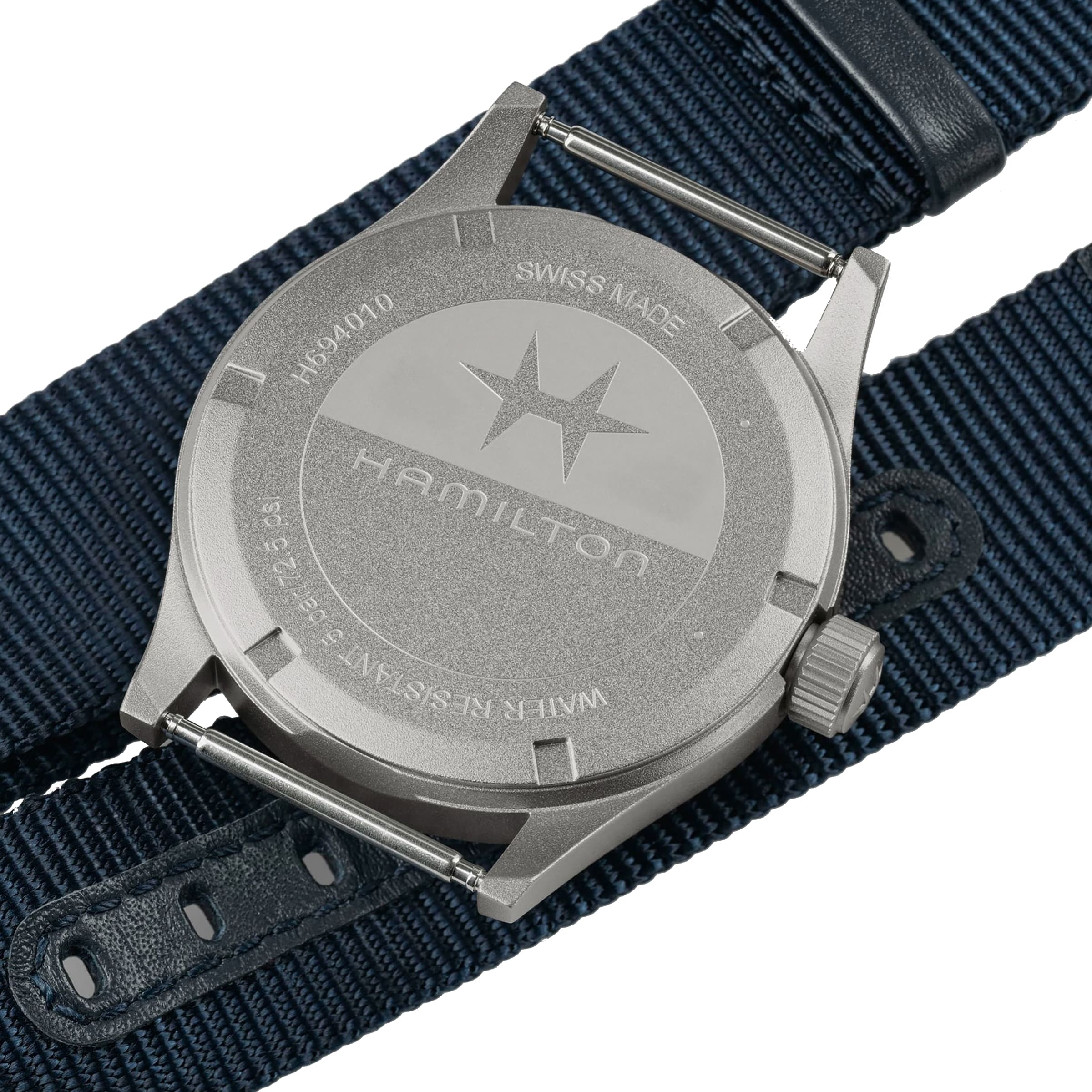 Close-up of the back of a Hamilton Khaki Field Quartz 38mm case with engravings, placed beside a blue NATO strap—highlighting its military-inspired design.