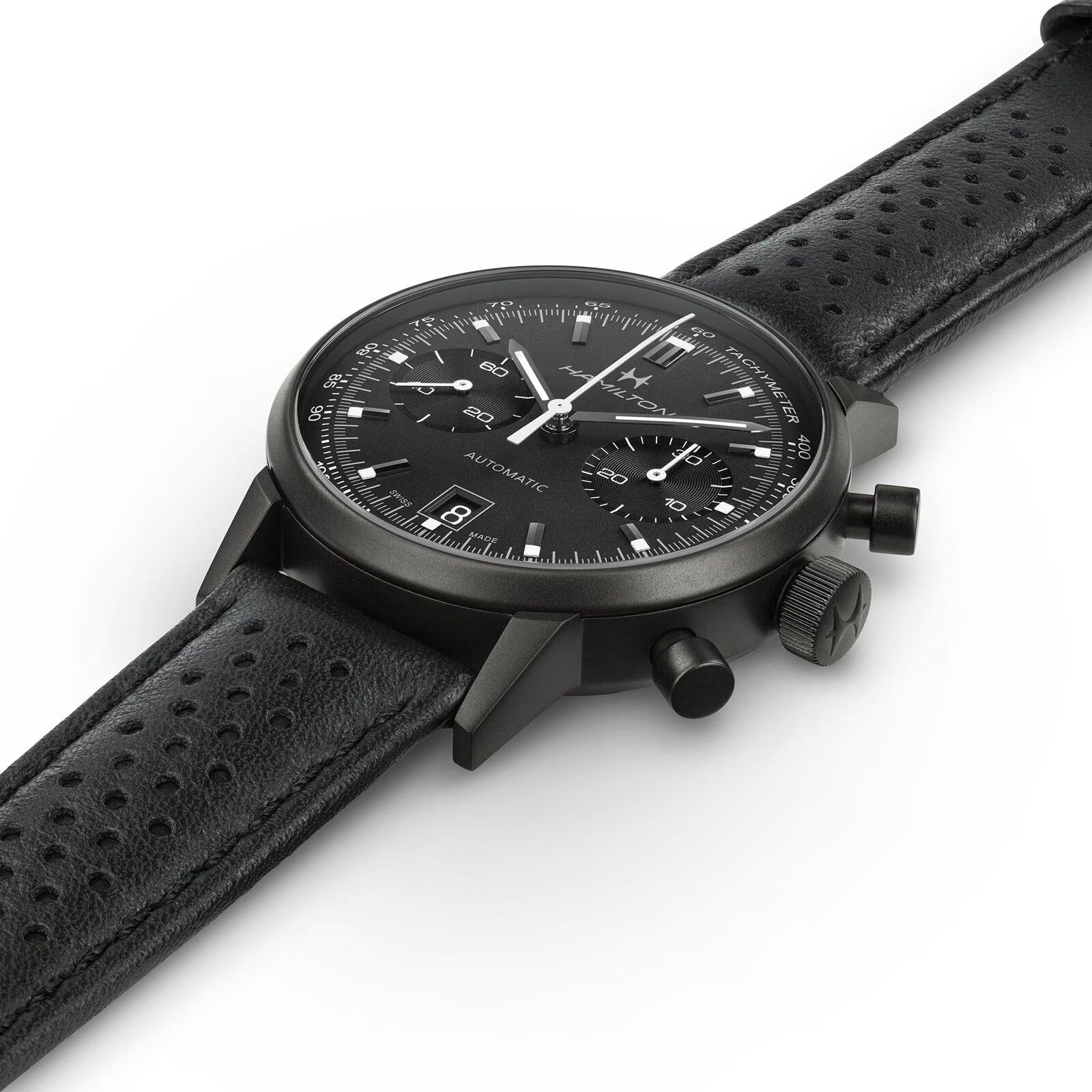 The Hamilton American Classic Intra-Matic Auto Chrono, a black chronograph wristwatch with a perforated leather strap, is photographed at an angle on a white background.