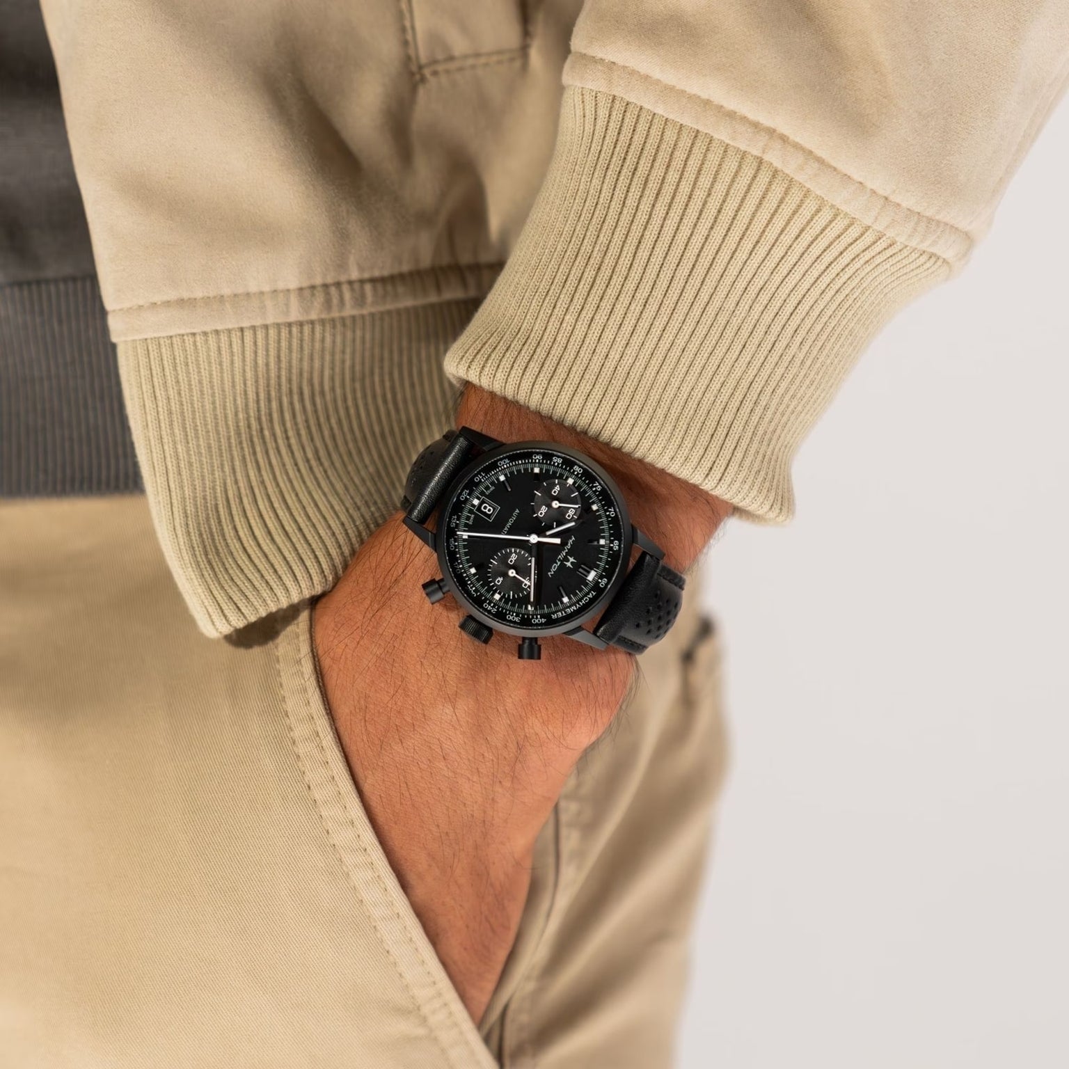 A person wearing a Hamilton American Classic Intra-Matic Auto Chrono with a black band, hand in the pocket of beige pants.