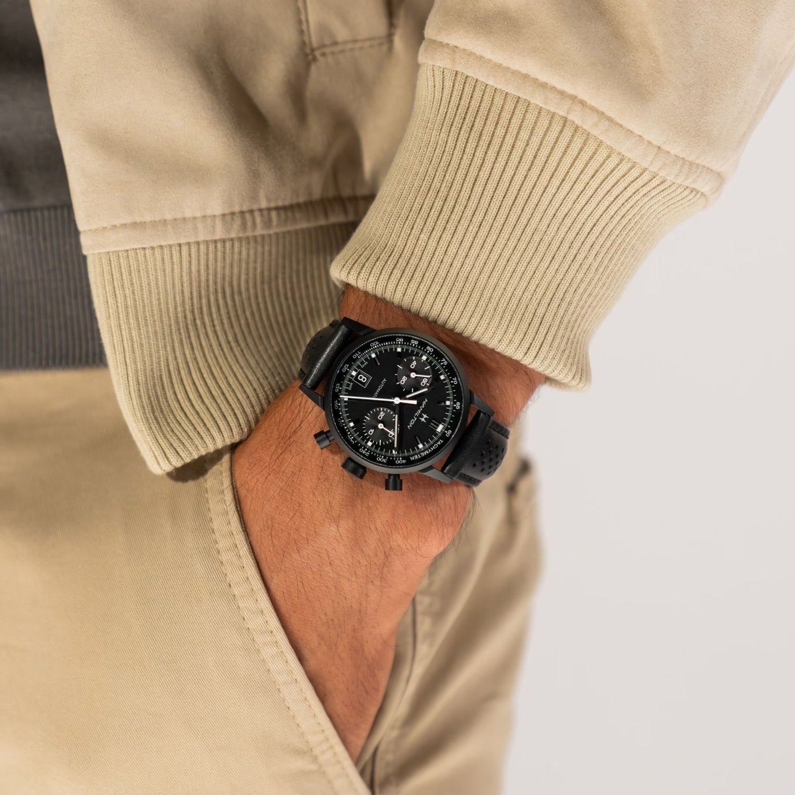 A person wearing a Hamilton American Classic Intra-Matic Auto Chrono with a black band, hand in the pocket of beige pants.