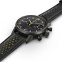 The Hamilton American Classic Intra-Matic Auto Chrono is a black chronograph wristwatch with yellow accents and a perforated leather strap, displayed on a white background.