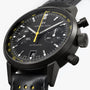 Hamilton American Classic Intra-Matic Auto Chrono chronograph watch with yellow accents, black leather strap, and visible date display.