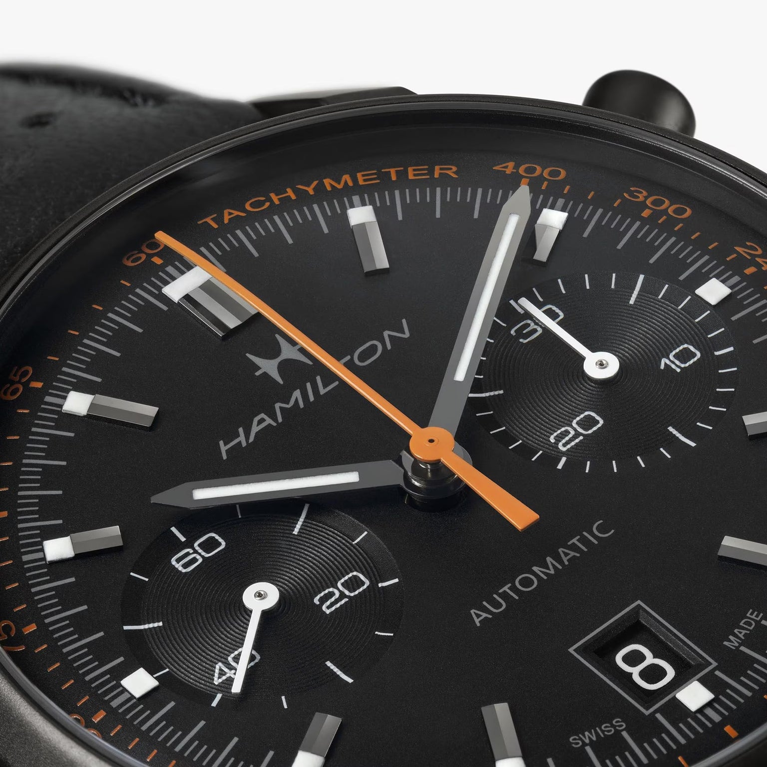 Close-up of a Hamilton American Classic Intra-Matic Auto Chrono watch in black with orange and white accents, featuring a date display at 4 o’clock.