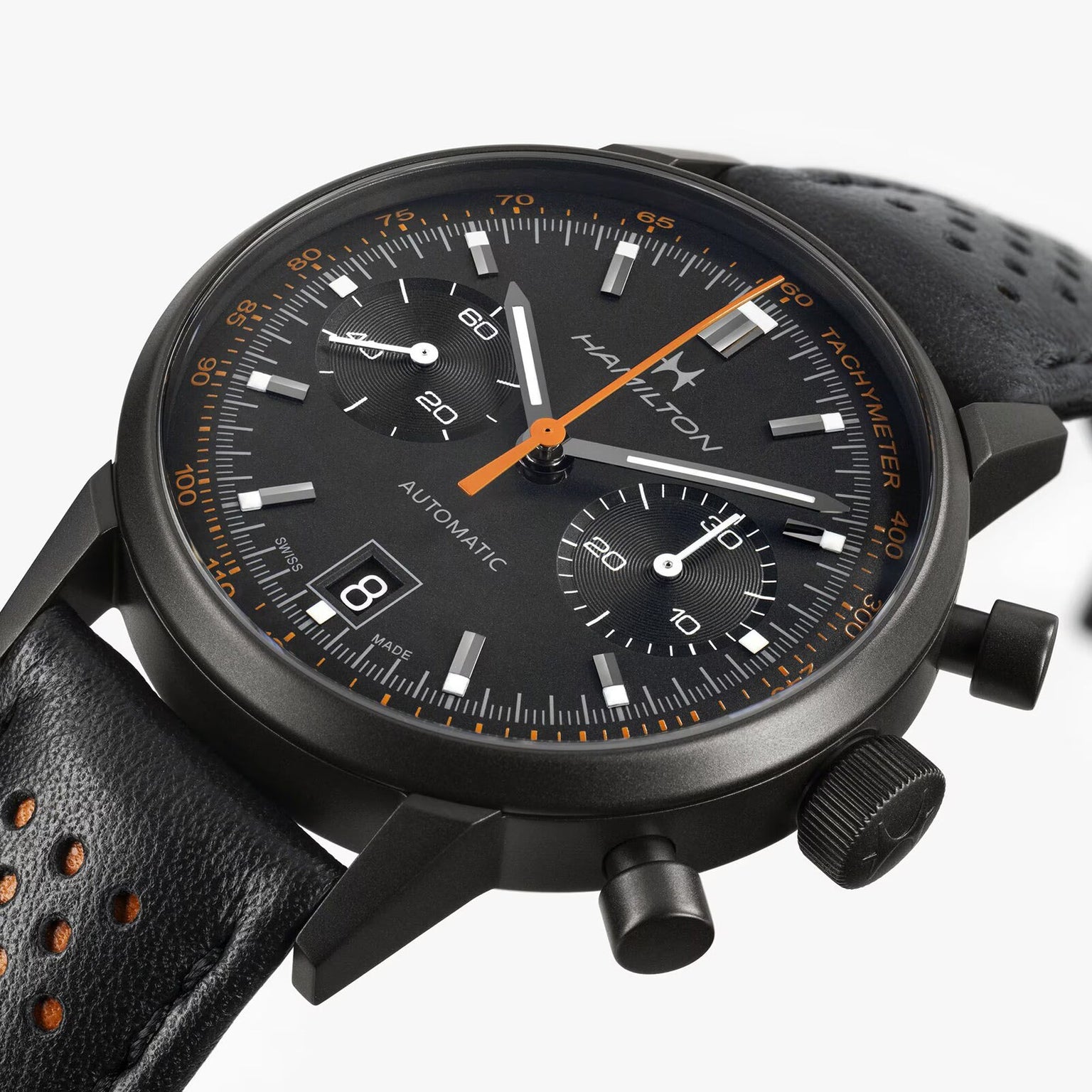 Close-up of the Hamilton American Classic Intra-Matic Auto Chrono, a black chronograph watch featuring a perforated leather strap and orange accents.