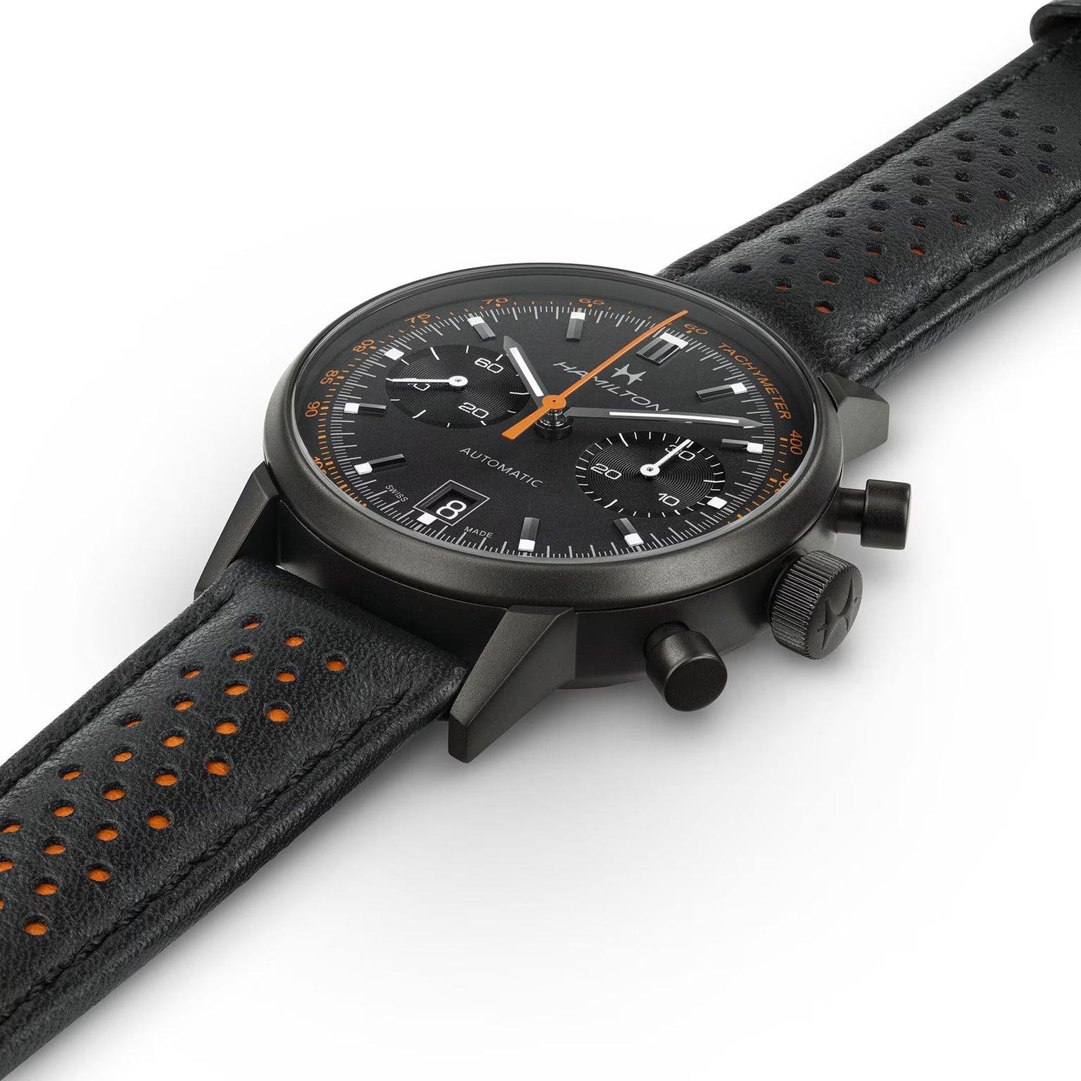 The Hamilton American Classic Intra-Matic Auto Chrono is a black chronograph wristwatch featuring a perforated leather strap and bold orange accents on the dial and strap lining.