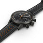The Hamilton American Classic Intra-Matic Auto Chrono is a black chronograph wristwatch featuring a perforated leather strap and bold orange accents on the dial and strap lining.