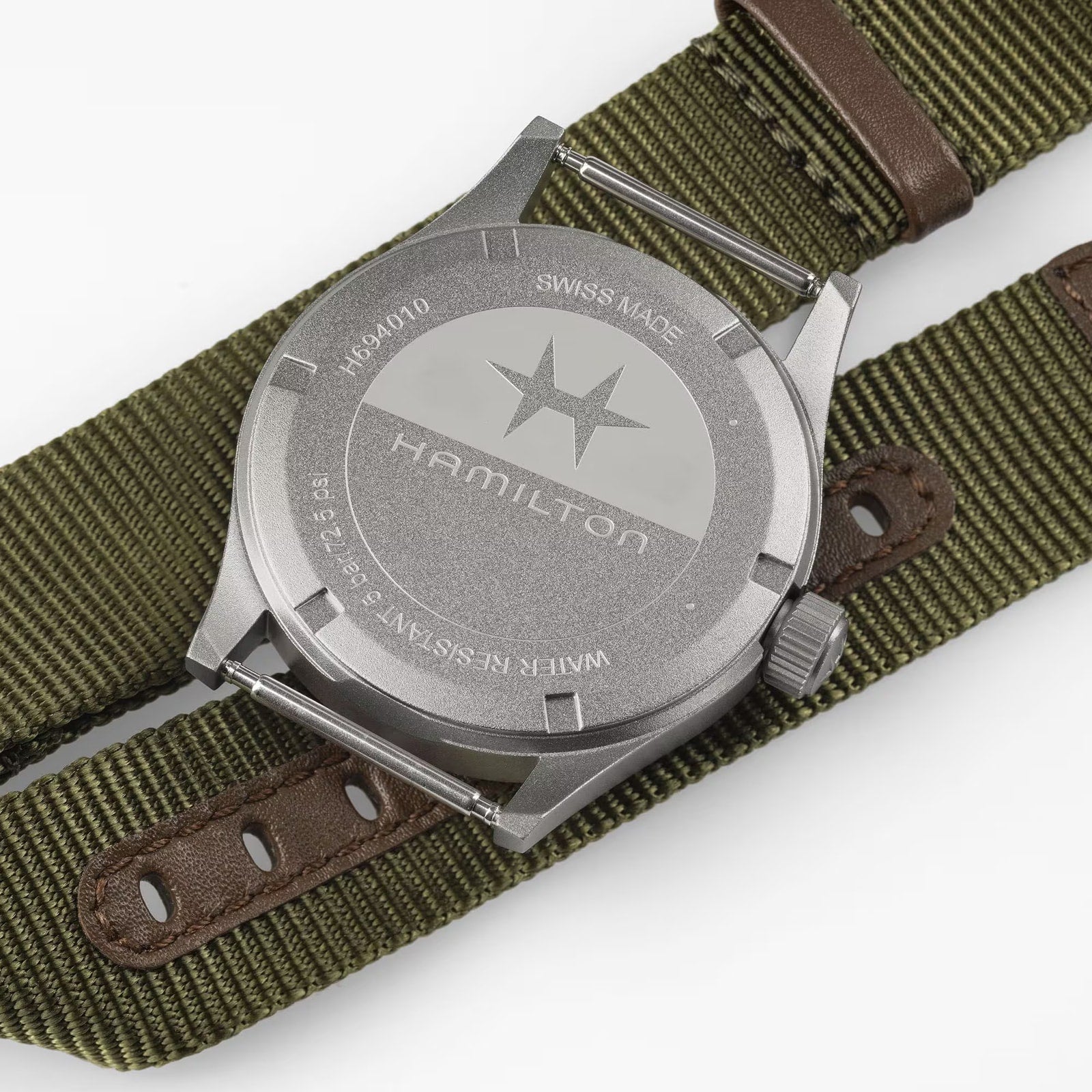Back of a Hamilton Khaki Field Quartz 38mm wristwatch on an olive green nylon strap with brown leather accents.