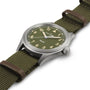 The Hamilton Khaki Field Quartz 38mm watch features a green dial, fabric strap, and silver case, displayed at an angle on a white background.