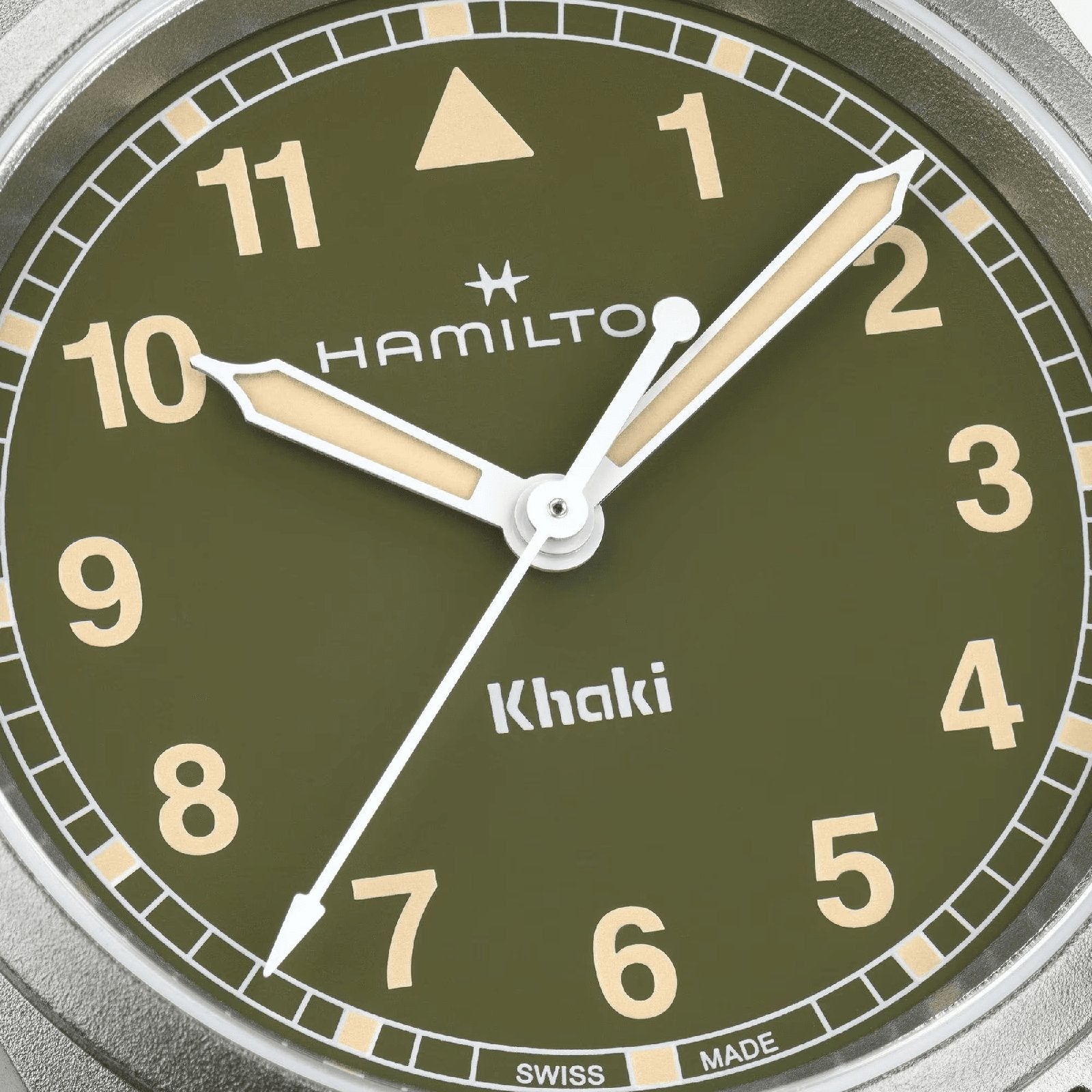 Close-up of the Hamilton Khaki Field Quartz 33mm watch face with white hands, beige indices, Arabic numerals, and a green background—highlighting its military heritage. The time shown is about 10:10:36.