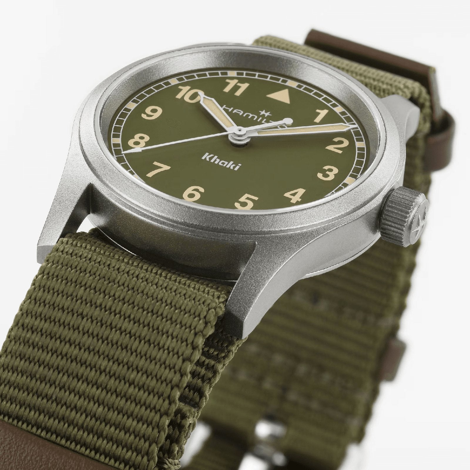 A close-up of the Hamilton Khaki Field Quartz 33mm wristwatch features an olive green face, tan numbers, silver casing, and an olive green fabric strap, highlighting its military-inspired design. The face displays Hamilton and Khaki.