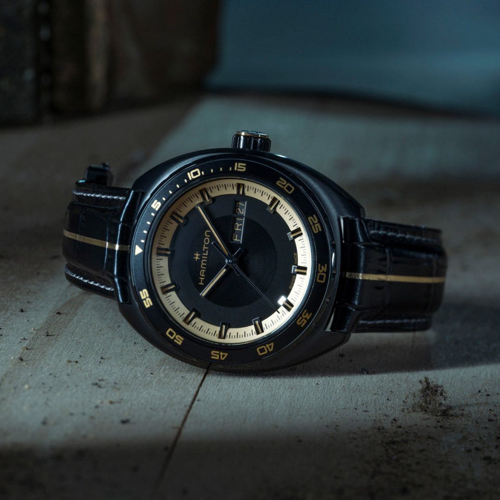 Hamilton watch with black leather strap on a textured surface