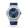 The Hublot Classic Fusion Titanium Blue features a blue sunray dial with silver markers, date display, and a blue leather strap in a titanium case, shown on a white background.
