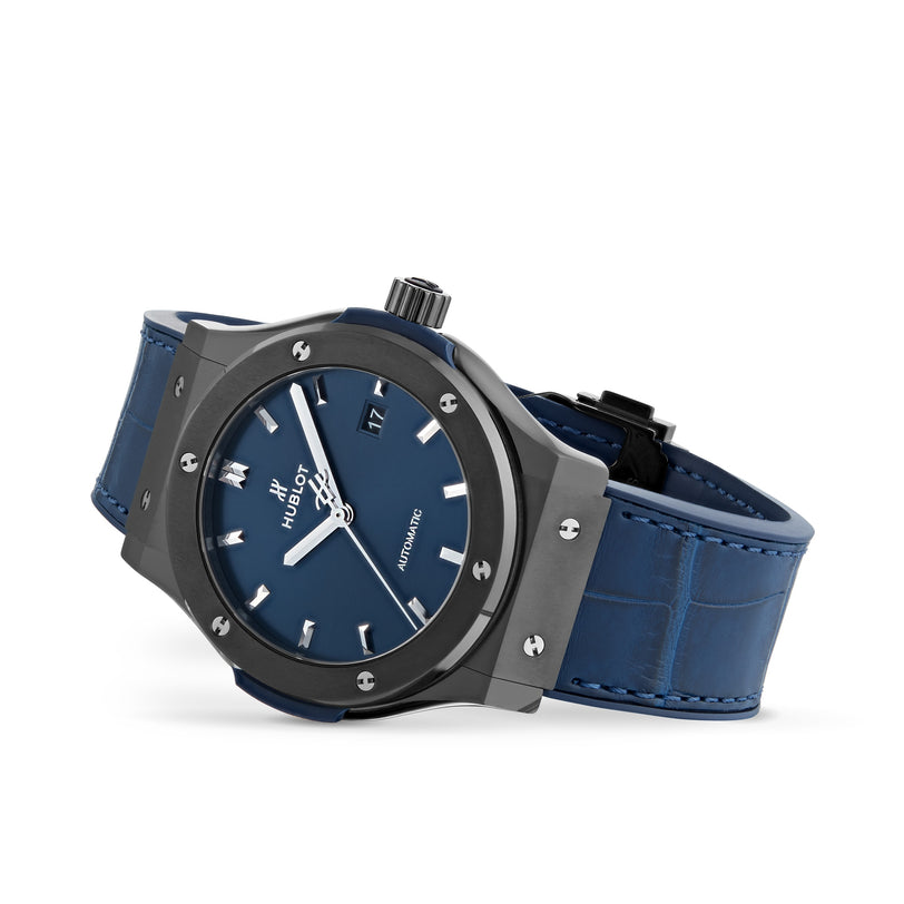 A Hublot Classic Fusion Ceramic Blue wristwatch with a blue leather strap and minimalist dial rests on its side against a white background, showcasing the precision of HUB1112 automatic movement.