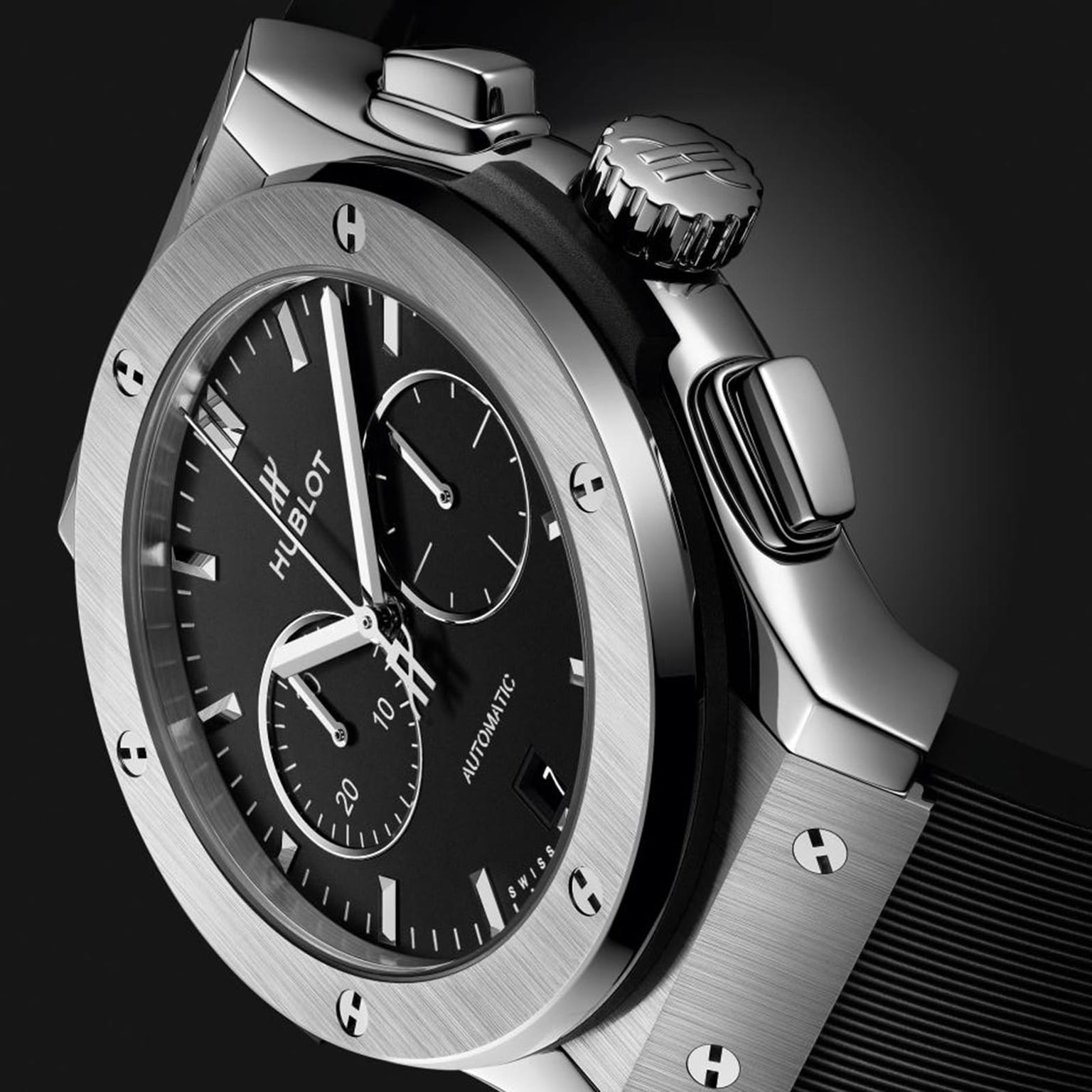 Close-up of a Hublot Classic Fusion Chronograph Titanium wristwatch with a black dial, titanium case, chronograph subdials, and black strap, set against a dark background.