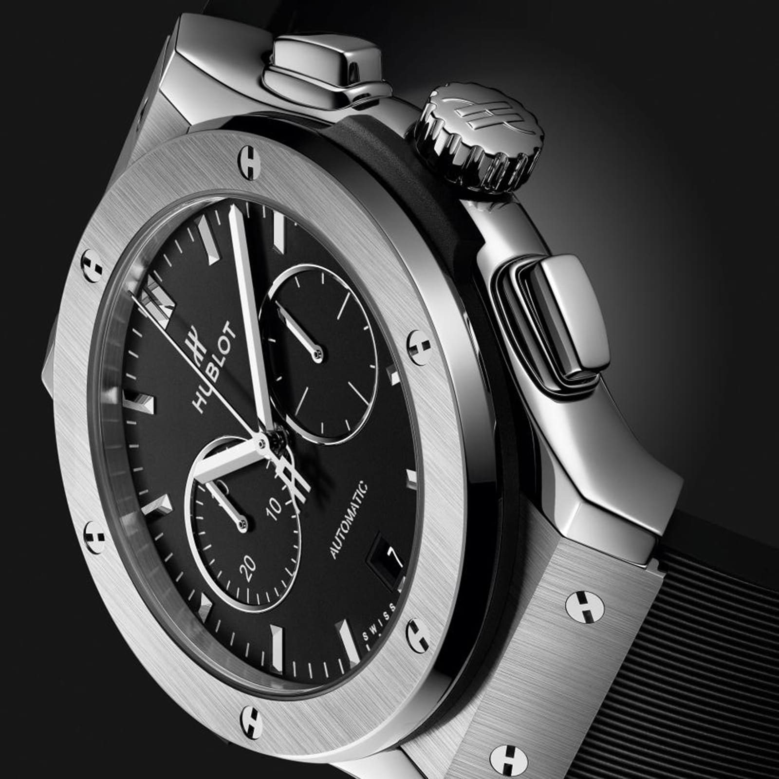 Close-up of a Hublot Classic Fusion Chronograph Titanium wristwatch with a black dial, titanium case, chronograph subdials, and black strap, set against a dark background.