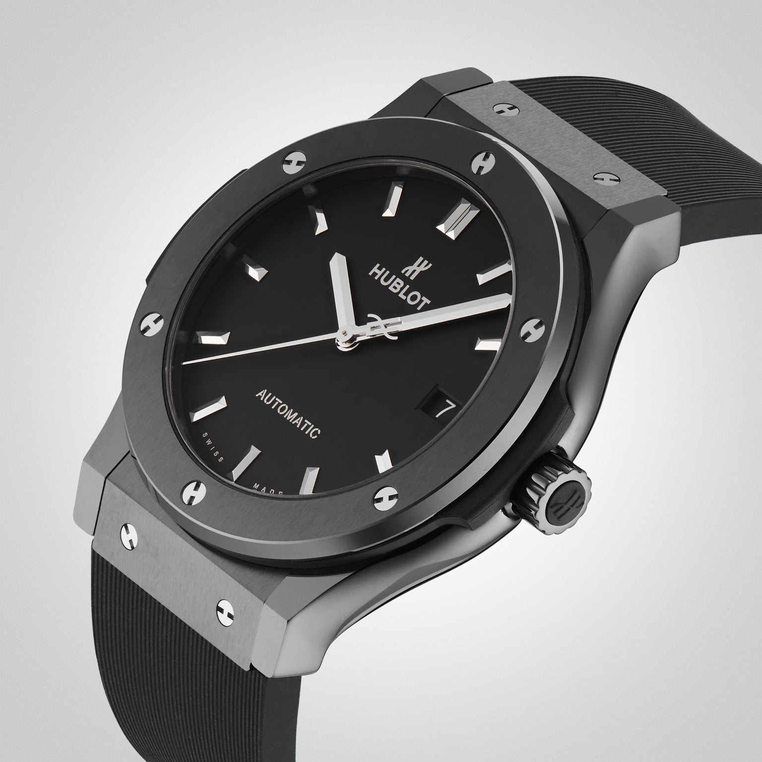 The Hublot Classic Fusion Black Magic, featuring a black ceramic case, black dial with silver hour markers, and a black rubber strap, is displayed against a light gray background.