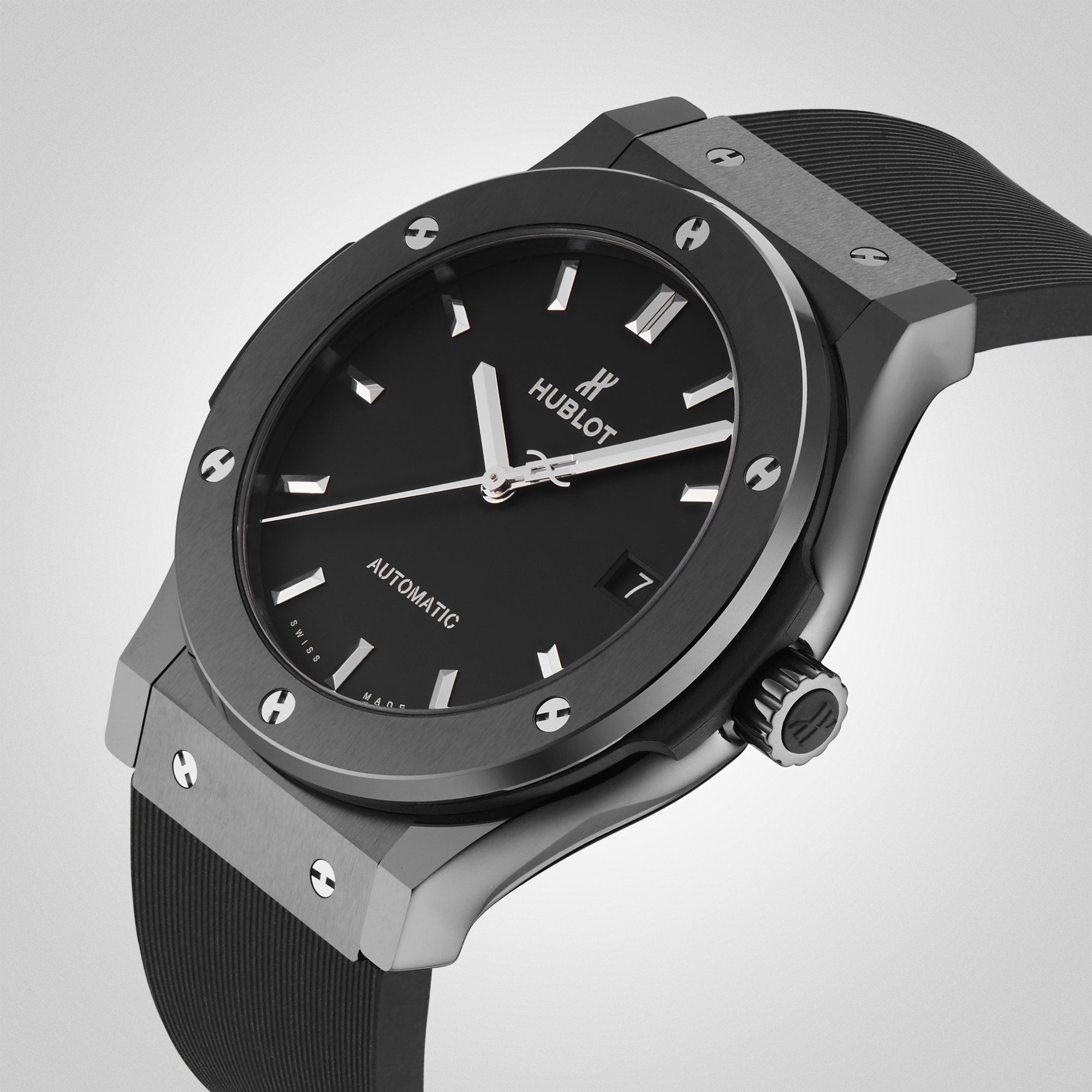 The Hublot Classic Fusion Black Magic, featuring a black ceramic case, black dial with silver hour markers, and a black rubber strap, is displayed against a light gray background.