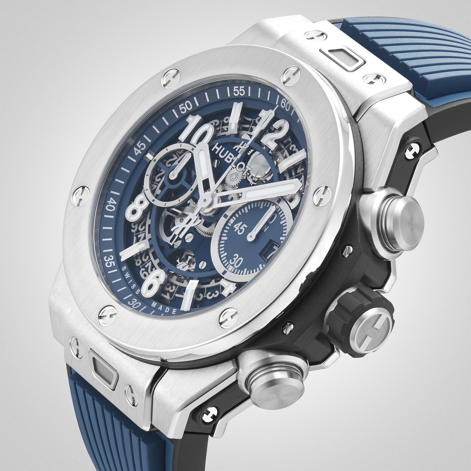 A close-up of the Hublot Big Bang Unico Titanium Blue wristwatch, featuring a blue rubber strap, titanium case, and skeleton dial that reveals its intricate inner mechanics.