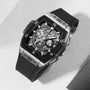The Hublot Spirit Of Big Bang Titanium Ceramic is a luxury skeleton watch with a square stainless steel case, exposed movement, sapphire crystal dial, and black rubber strap, showcased on a light surface.