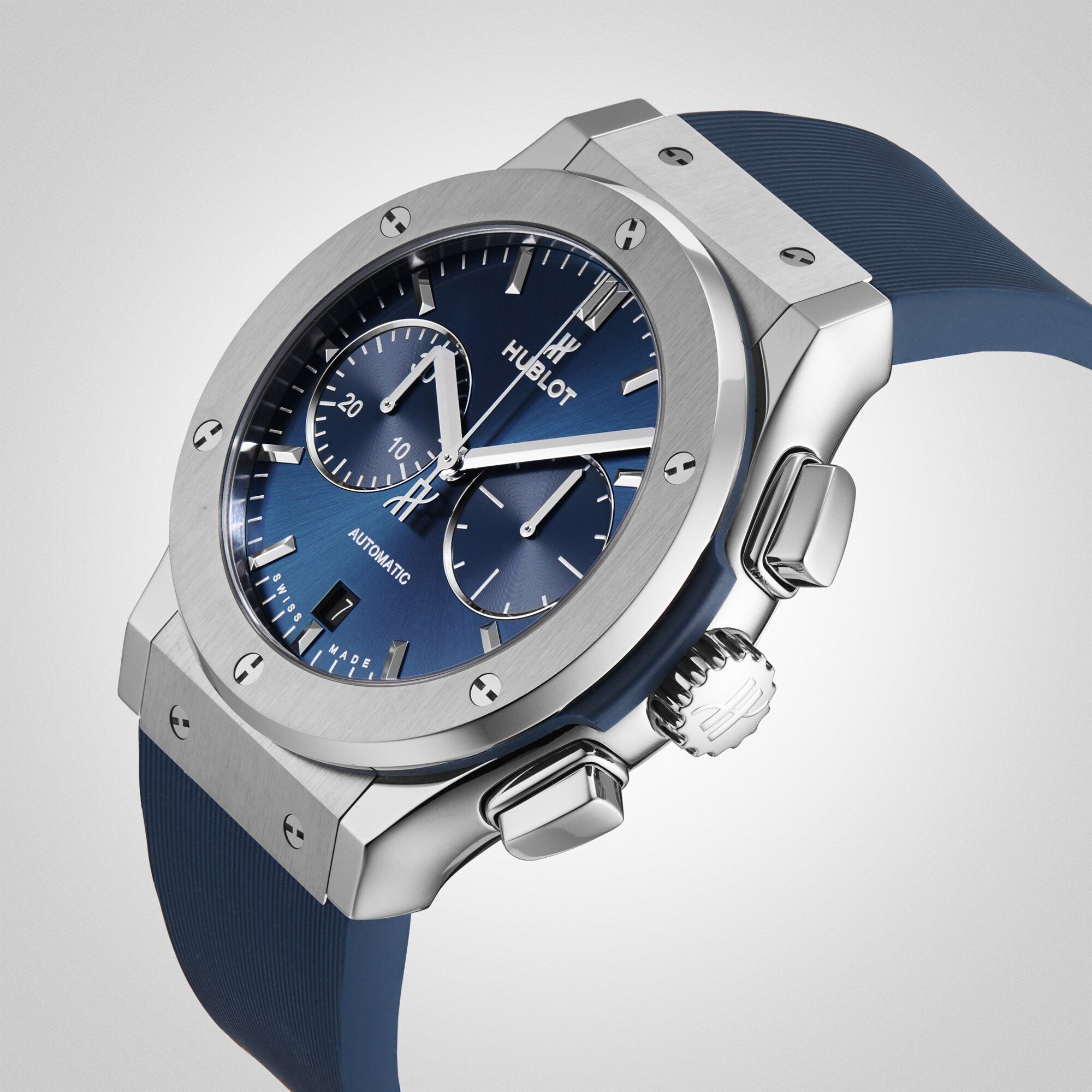 The Hublot Classic Fusion Chronograph Titanium Blue features a titanium case, blue dial, blue rubber strap, two subdials, silver hour markers, and precise chronograph movement.