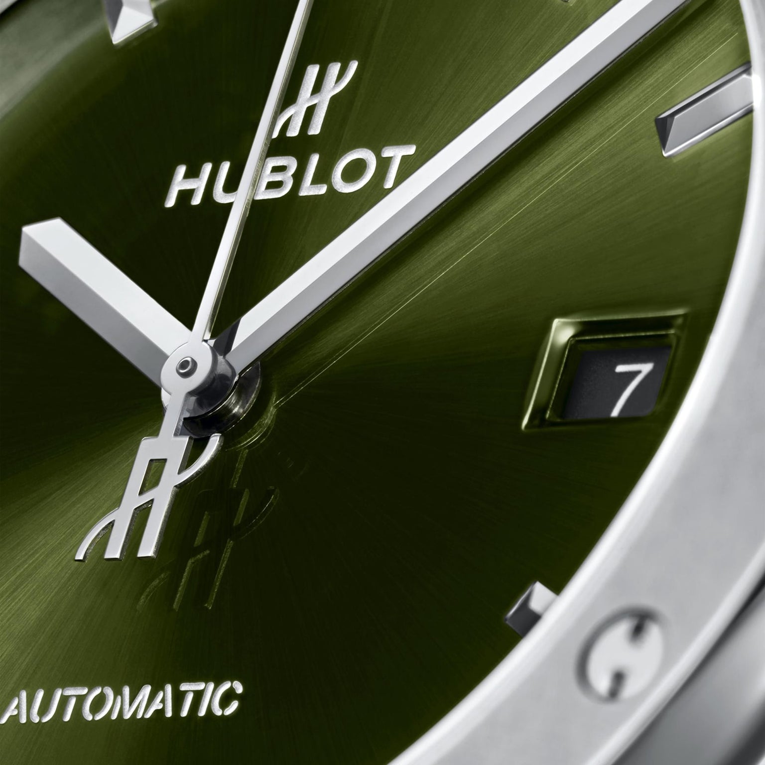 Close-up of a green Hublot Classic Fusion Titanium Green watch face with silver hands, hour markers, date at 7, HUBLOT branding, and powered by an automatic movement.