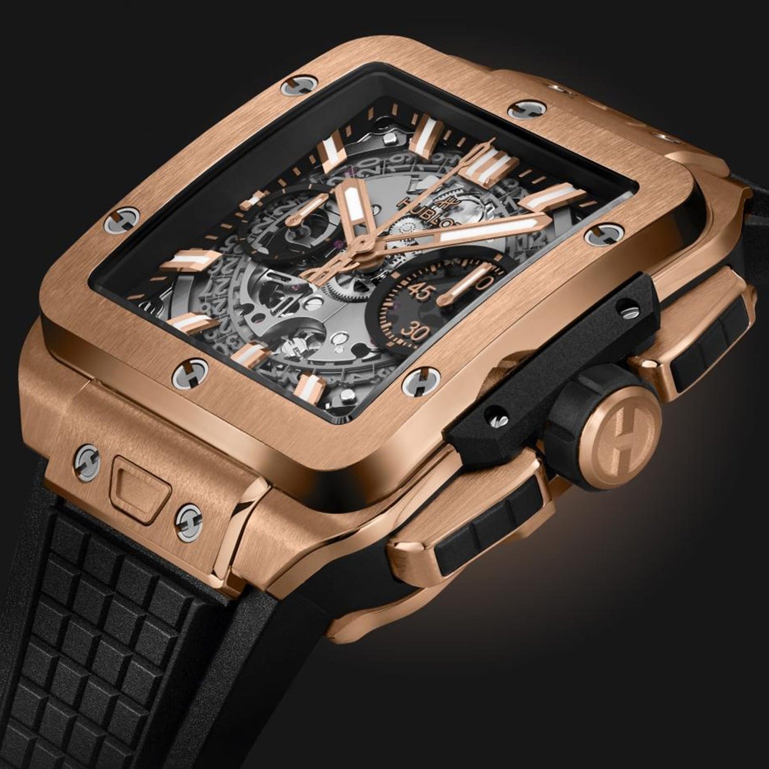 A close-up of the Hublot Square Bang Unico King Gold, featuring an 18K King Gold rectangular case, exposed Unico 2 calibre movement, black accents, and a black textured strap.