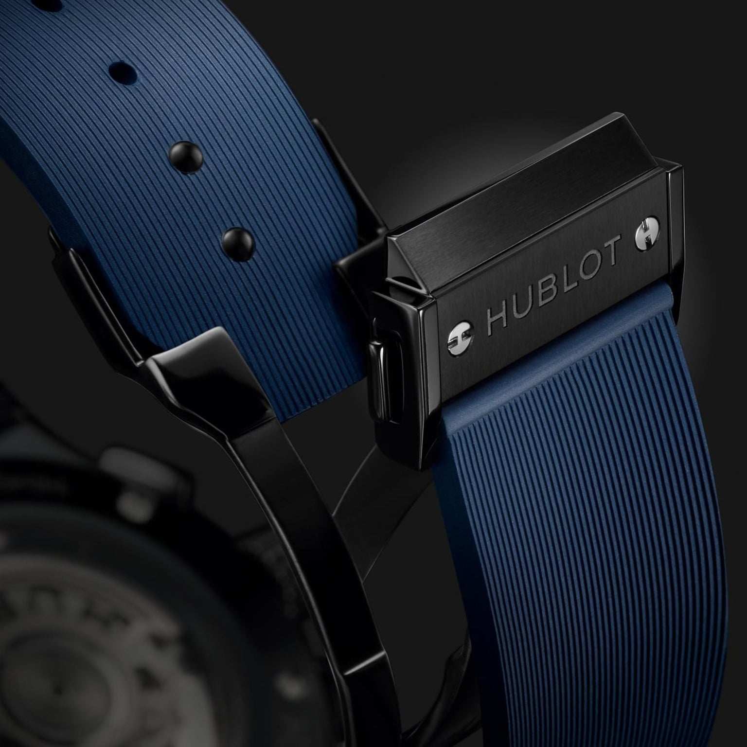 Close-up of the Hublot Classic Fusion Ceramic Blue Chronographs clasp, featuring a blue textured rubber strap, black metal buckle with engraved Hublot logo, and glimpses of its blue sunray dial.