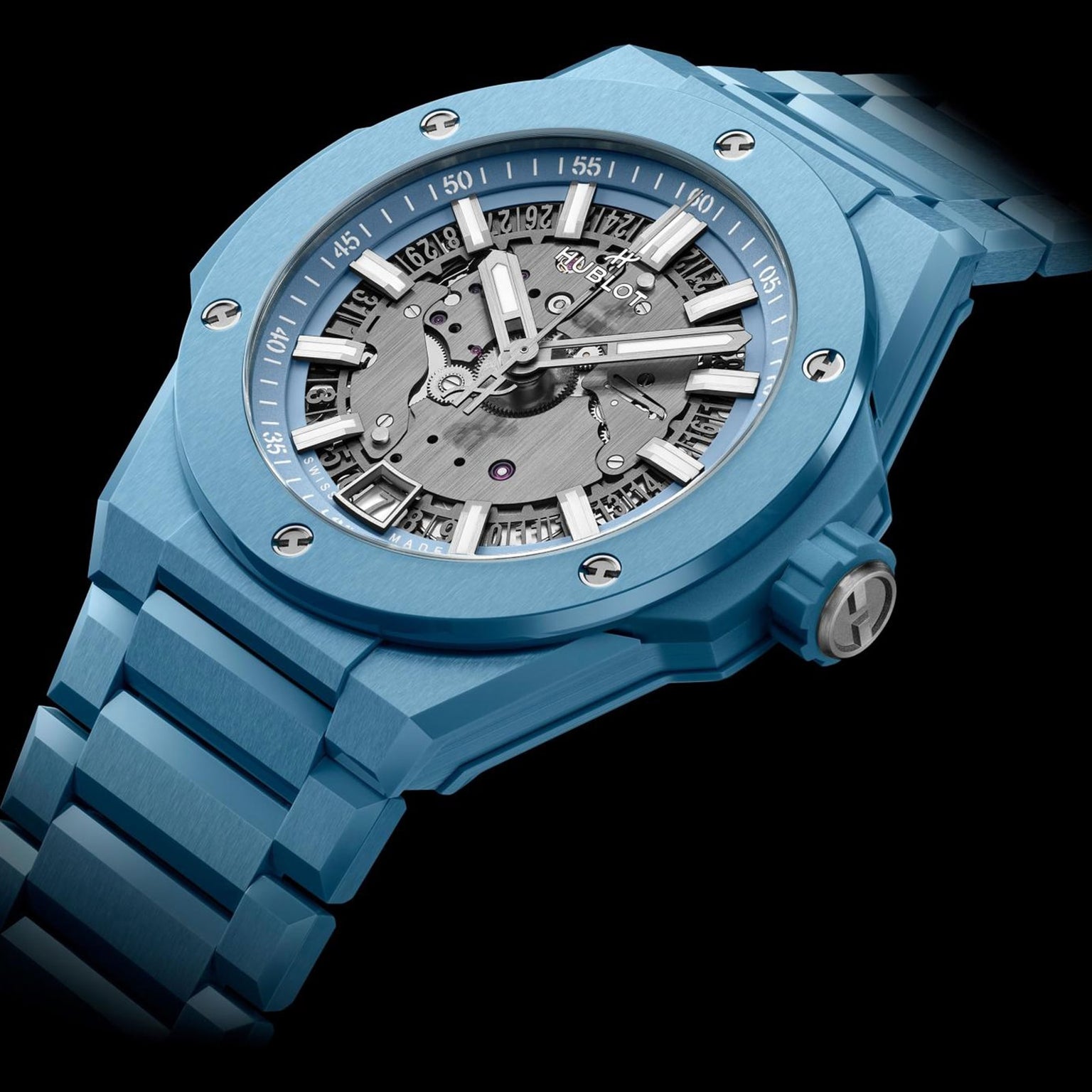 The Hublot Big Bang Integrated Time Only Sky Blue Ceramic features a blue ceramic case, visible automatic movement, silver hour markers, and a metal bracelet, photographed against a black background.