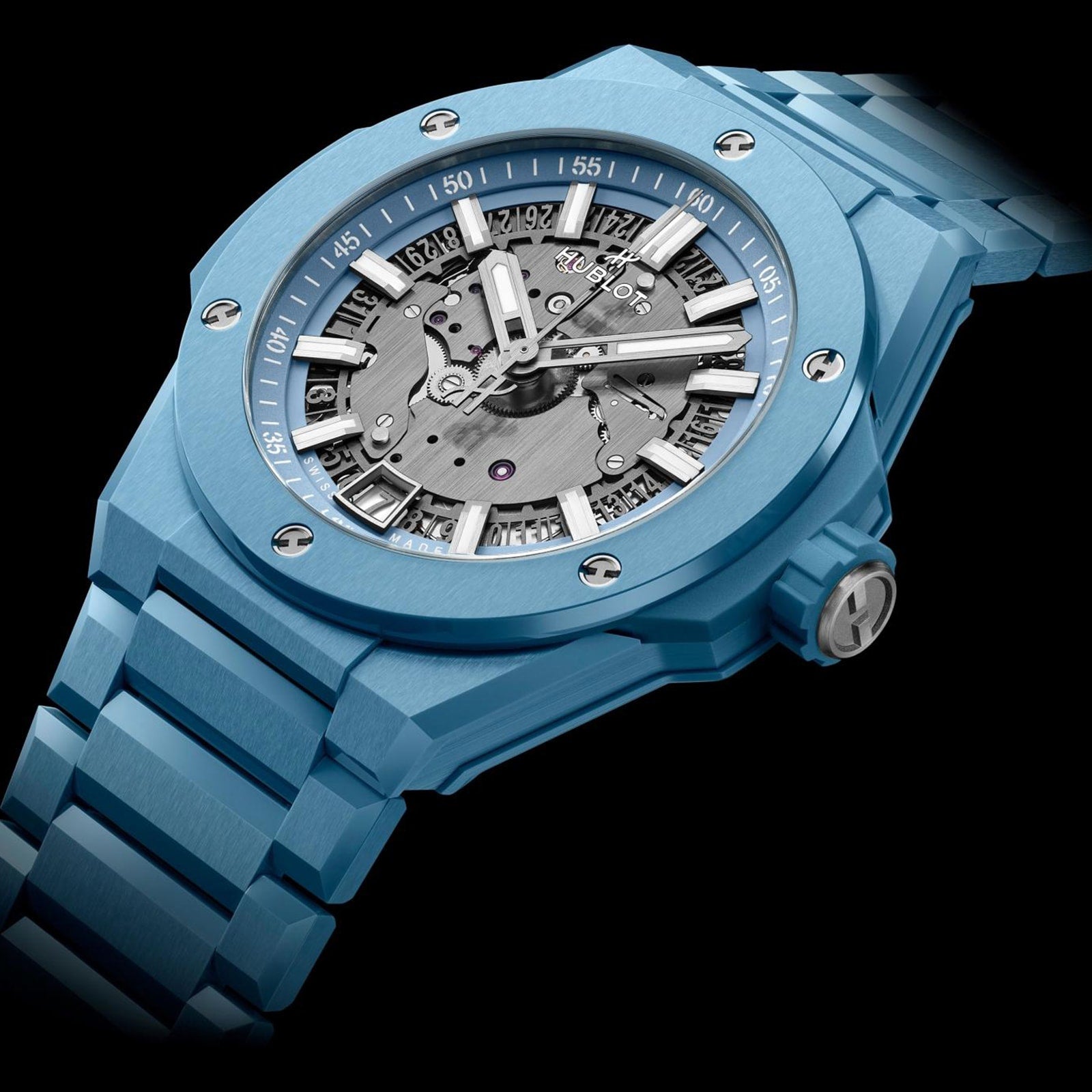 The Hublot Big Bang Integrated Time Only Sky Blue Ceramic features a blue ceramic case, visible automatic movement, silver hour markers, and a metal bracelet, photographed against a black background.