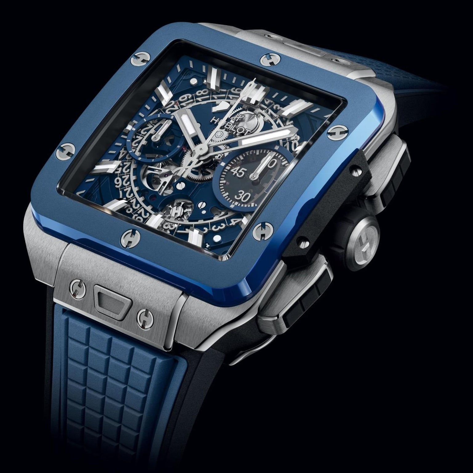 The Hublot Square Bang Unico Titanium Blue Ceramic luxury watch features exposed gears, blue ceramic accents, a chronograph dial, sapphire crystal, and a textured blue rubber strap, elegantly displayed at an angle against a black background.