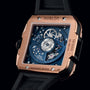 A close-up of the Hublot Square Bang Unico King Gold Blue watch displays its exposed mechanical movement through a transparent case back, highlighting its 18k King Gold craftsmanship.