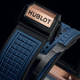 Close-up of the Hublot Square Bang Unico King Gold Blue watch clasp, featuring an 18k King Gold plate, black casing, and a textured blue rubber strap.