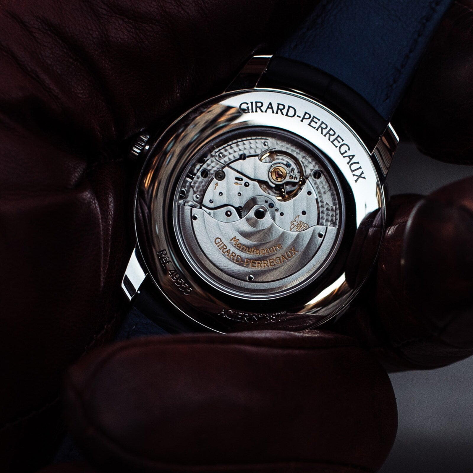 A gloved hand holds the Girard-Perregaux 1966 40 wristwatch, displaying the calibre GP0330 movement and engraved brand name through its stainless steel case back.