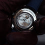A gloved hand holds the Girard-Perregaux 1966 40 wristwatch, displaying the calibre GP0330 movement and engraved brand name through its stainless steel case back.