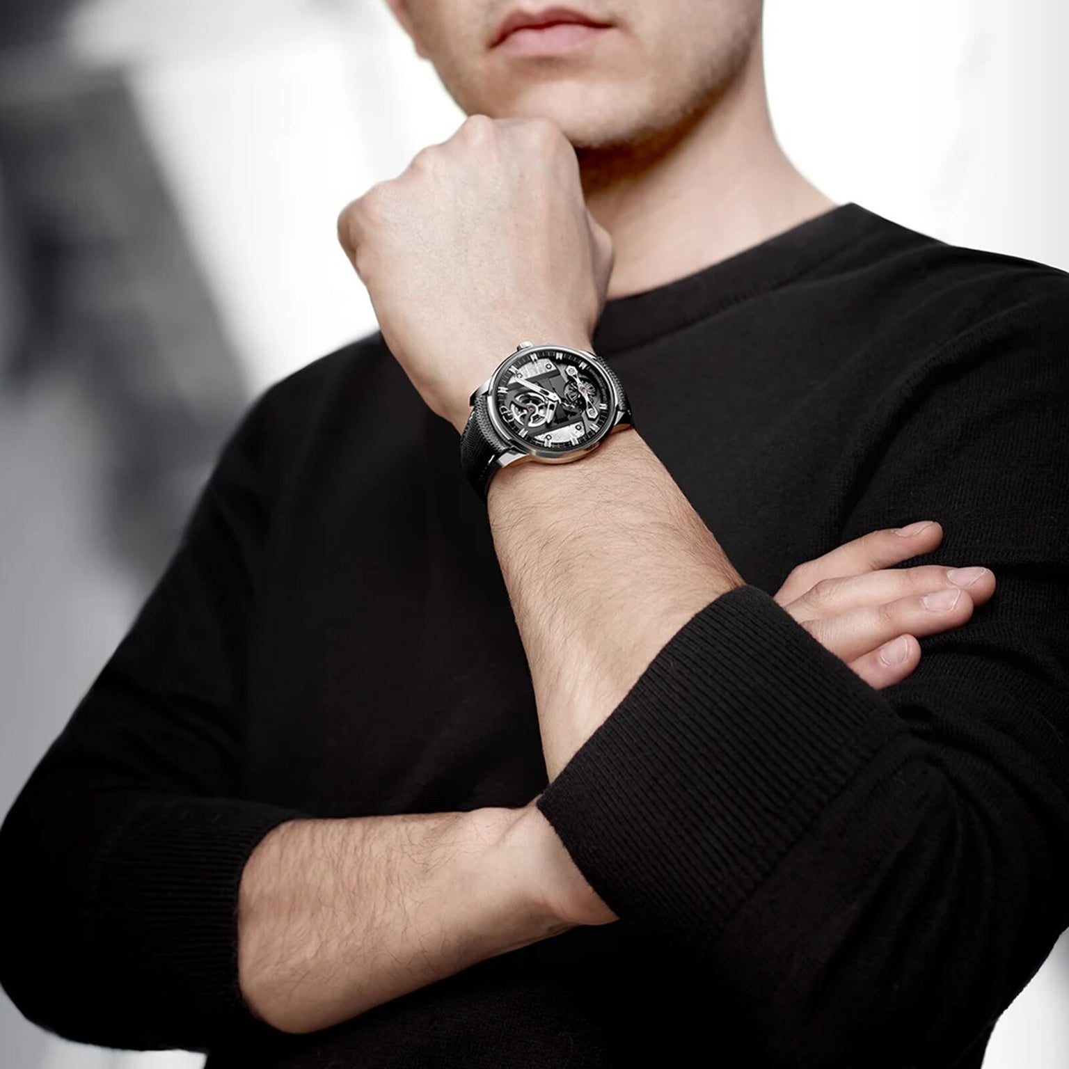 A person in a black long-sleeve shirt crosses their arms, displaying the Girard-Perregaux Free Bridge Meteorite wristwatch on their left wrist.