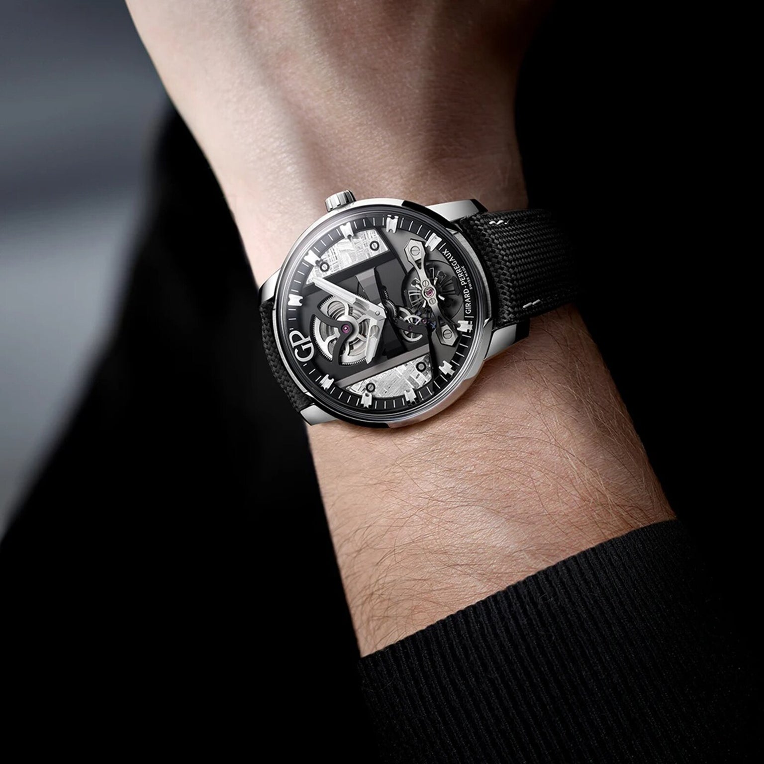 A close-up of a wrist adorned with the Girard-Perregaux Free Bridge Meteorite, featuring avant-garde design from the Bridges Collection, with a visible mechanical movement and a textured black strap.